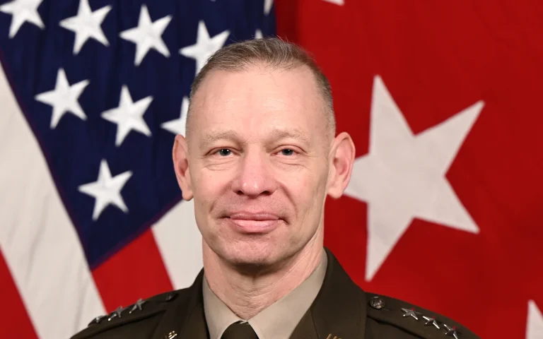 Official portrait of U.S. Army Lt. Gen. Brett Sylvia in dress uniform in front of the American flag