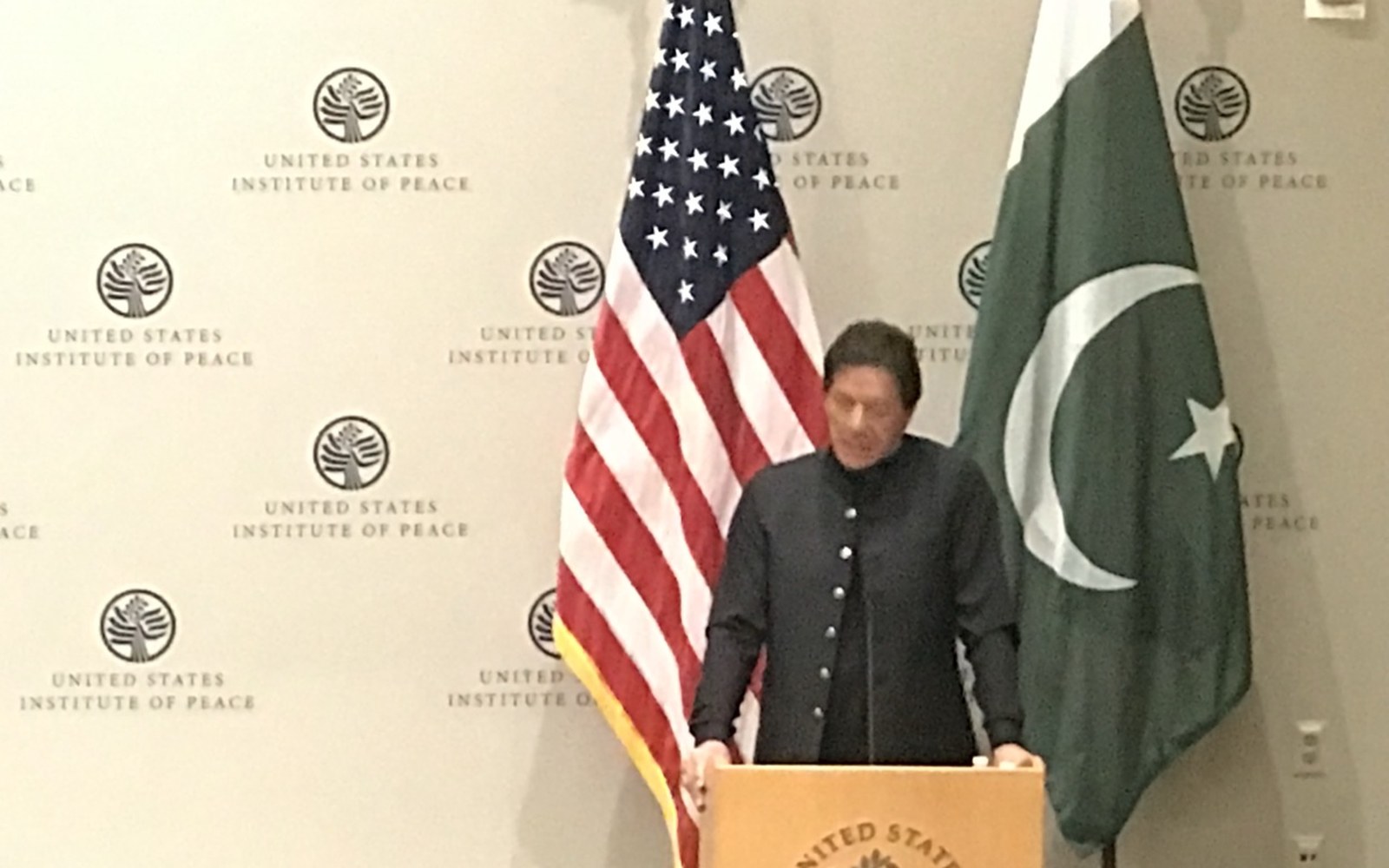 Imran Khan speaking at a podium between U.S. and Pakistan flags